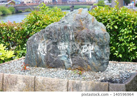 一座刻有「紀念碑」字樣的天然石碑,矗立在河邊。 一座刻有「紀念碑」字樣的天然石碑,矗立在河邊。 140596964