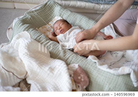 一位母親正在幫新生兒換衣服。 140596969