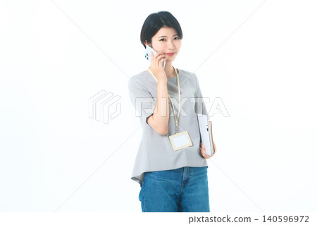 一位年輕女子在白色背景前一邊打電話一邊看著鏡頭。 一位年輕女子在白色背景前一邊打電話一邊看著鏡頭。 140596972