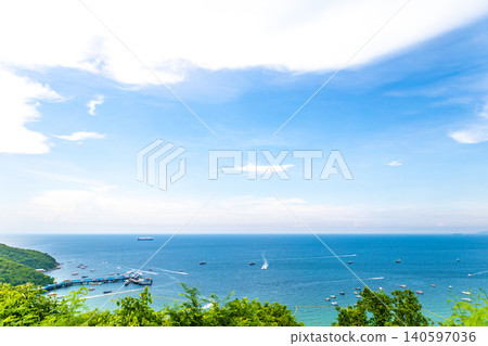 A beach surrounded by greenery and the blue sea. 140597036