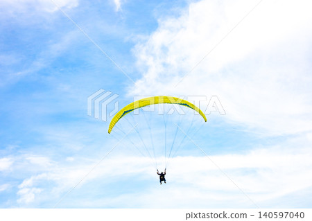A paraglider flies in the blue sky. 140597040