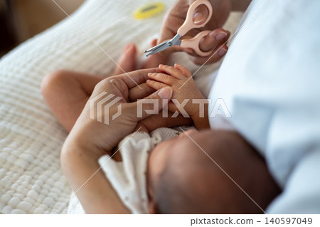 A mother is holding her newborn baby and cutting her nails. A mother is holding her newborn baby and cutting her nails. 140597049