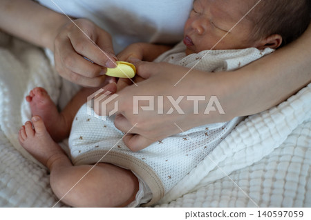 一位母親一邊抱著新生兒一邊修指甲。 140597059