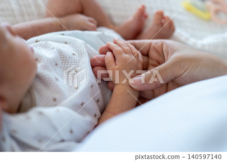 A mother's hand holding the hand of her sleeping newborn. A mother's hand holding the hand of her sleeping newborn. 140597140