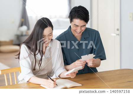 A middle-aged couple keeping track of their household finances in the living room. A middle-aged couple keeping track of their household finances in the living room. 140597158