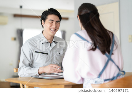 A housewife and a construction worker discussing renovation plans. A housewife and a construction worker discussing renovation plans. 140597171