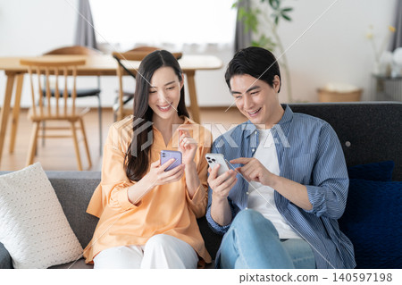 A middle-aged couple watching a smartphone in the living room A middle-aged couple watching a smartphone in the living room 140597198