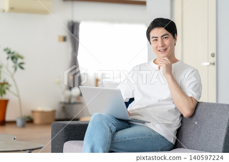 Middle-aged man looking at a computer in the living room Middle-aged man looking at a computer in the living room 140597224