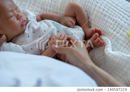 母親的手握著熟睡新生兒的手。 140597229