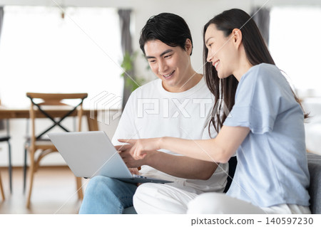 Middle-aged couple looking at a computer in the living room Middle-aged couple looking at a computer in the living room 140597230