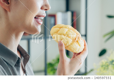 A young woman eating a melon bun at home 140597331