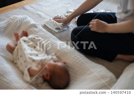 一位母親在熟睡的新生兒身旁疊衣服。 一位母親在熟睡的新生兒身旁疊衣服。 140597410