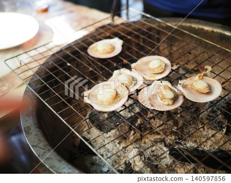 Grilled scallop on shell over charcoal grill, seafood cooking with smoke and rustic outdoor style Grilled scallop on shell over charcoal grill, seafood cooking with smoke and rustic outdoor style 140597856