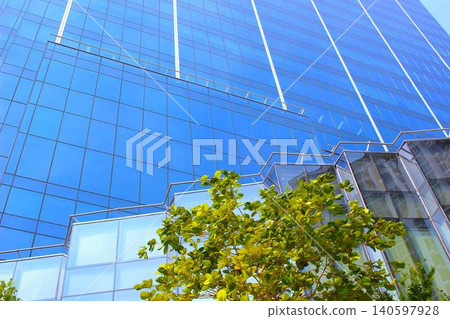 A stylish commercial building with a blue curtain wall, viewed from below. A stylish commercial building with a blue curtain wall, viewed from below. 140597928