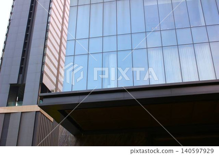 A stylish commercial building with a blue curtain wall, viewed from below. A stylish commercial building with a blue curtain wall, viewed from below. 140597929