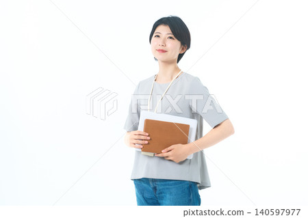 A young woman looking up, holding documents, against a white background. A young woman looking up, holding documents, against a white background. 140597977
