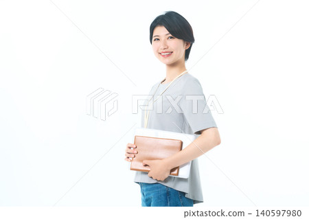 A young woman smiling to the side, holding documents, against a white background. A young woman smiling to the side, holding documents, against a white background. 140597980