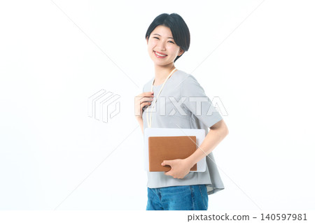 A smiling young woman with her hand on a neck strap against a white background. A smiling young woman with her hand on a neck strap against a white background. 140597981