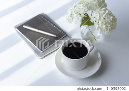 A workspace with Annabelle hydrangea, coffee, and a notebook. A workspace with Annabelle hydrangea, coffee, and a notebook. 140598002