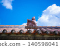 A Shisa statue (A) perched on a red tiled roof in Chinen, Okinawa. 140598041