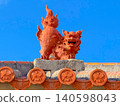 A Shisa statue (A) perched on a red tiled roof in Motobu, Okinawa. 140598043