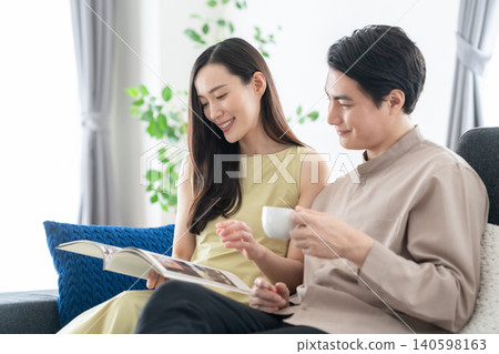 A middle-aged couple reading in the living room. 140598163
