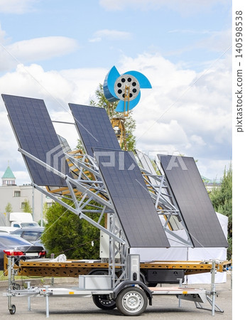 Solar panels on a trailer with wind turbine setup in an outdoor scene during the day Solar panels on a trailer with wind turbine setup in an outdoor scene during the day 140598538