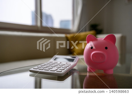 A piggy bank and calculator on the table, representing household budget management. A piggy bank and calculator on the table, representing household budget management. 140598663