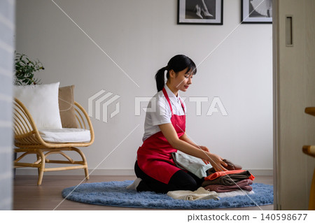 一位女士正在室內疊衣服。 140598677