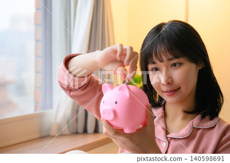 一位女士正在往存錢筒裡放硬幣。 140598691