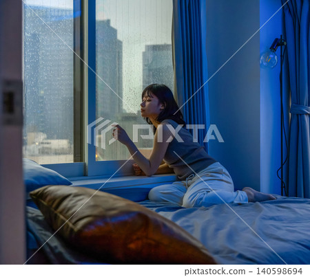 A woman gazing out the window on a rainy night. A woman gazing out the window on a rainy night. 140598694