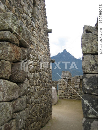 A path surrounded by the stone walls of the Machu Picchu ruins A path surrounded by the stone walls of the Machu Picchu ruins 140599028