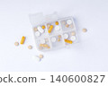 Pill box organizer with capsules and tablets on white background, daily medication and supplement 140600827