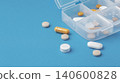 Pills and capsules with pill box organizer on blue background, daily medication and supplement 140600828