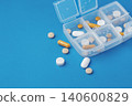 Pills and supplement spilling out of a pill organizer box on a blue background 140600829