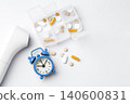 Pill box with digital thermometer, and alarm clock on white background, daily medication and supplement, top view 140600831