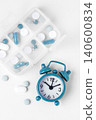 Top view of pill organizer and alarm clock on white background, Daily medication and supplement routine concept 140600834