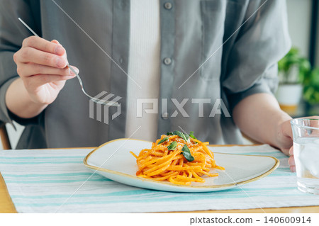 一位年輕女子午餐吃義大利麵。 一位年輕女子午餐吃義大利麵。 140600914
