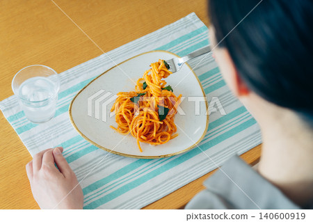 一位年輕女子午餐吃義大利麵。 一位年輕女子午餐吃義大利麵。 140600919
