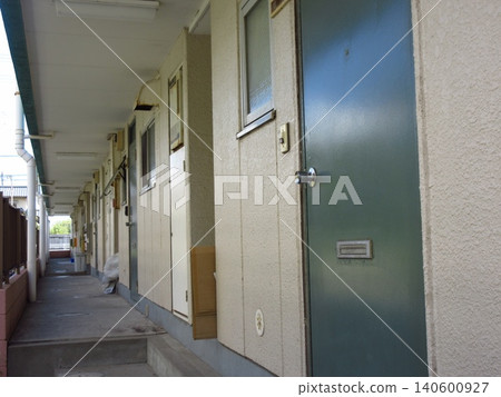 The exterior of an apartment building with a row of doors leading to the exterior corridor of the multi-unit building. 140600927