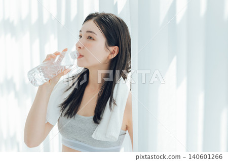 Woman drinking water by the window Woman drinking water by the window 140601266