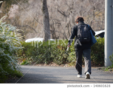 A middle-aged woman hurrying through a park in springtime. A middle-aged woman hurrying through a park in springtime. 140601628