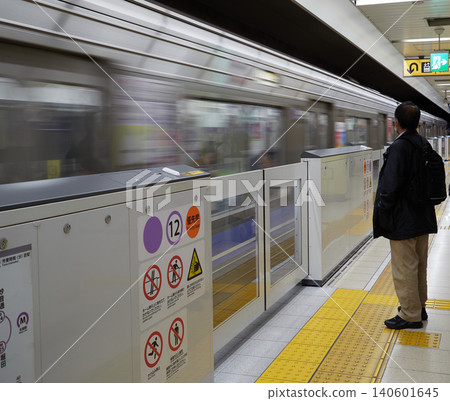 A male office worker waiting for a train on the platform of a Nagoya subway station on the Meijo Line. A male office worker waiting for a train on the platform of a Nagoya subway station on the Meijo Line. 140601645