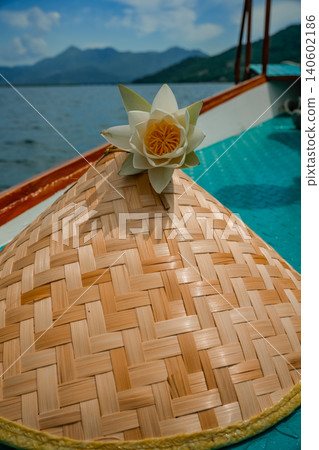 White water lily on straw hat on boat at lake with mountains scenic nature photo 140602186