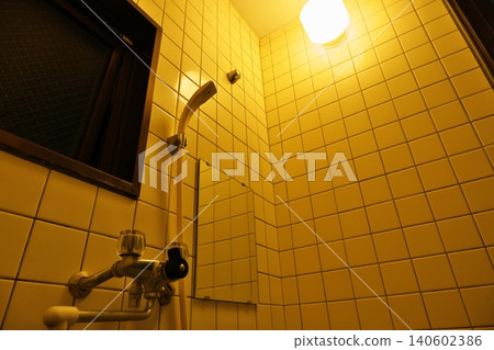 A nostalgic tiled bathroom bathed in the warm glow of a light bulb. A nostalgic tiled bathroom bathed in the warm glow of a light bulb. 140602386