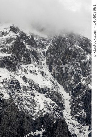 Vertical view the snow-capped peaks pierce dense, swirling mist. Vertical view the snow-capped peaks pierce dense, swirling mist. 140602961