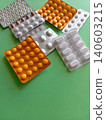 A bunch of pills are scattered on a green surface The pills are of different colors and shapes, and they appear to be in various stages of being opened. Concept of disarray and confusion 140603215