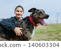 Happy Girl with dark hair in blue hoodie hugs her dog outdoors 140603304