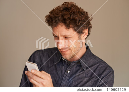 Mature man, smartphone and texting in studio for thinking, reading or scroll for search on web by background. Person, phone and check for email, notification or post on social network with mobile app Mature man, smartphone and texting in studio for thinking, reading or scroll for search on web by background. Person, phone and check for email, notification or post on social network with mobile app 140603329