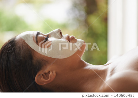 Skincare, cosmetic and woman with face mask at spa for glow, wellness and beauty routine with peace. Natural, pamper and female person relaxing for clay facial dermatology treatment at salon. 140603485